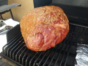 A freshly glazed ham, smoking on the barbecue