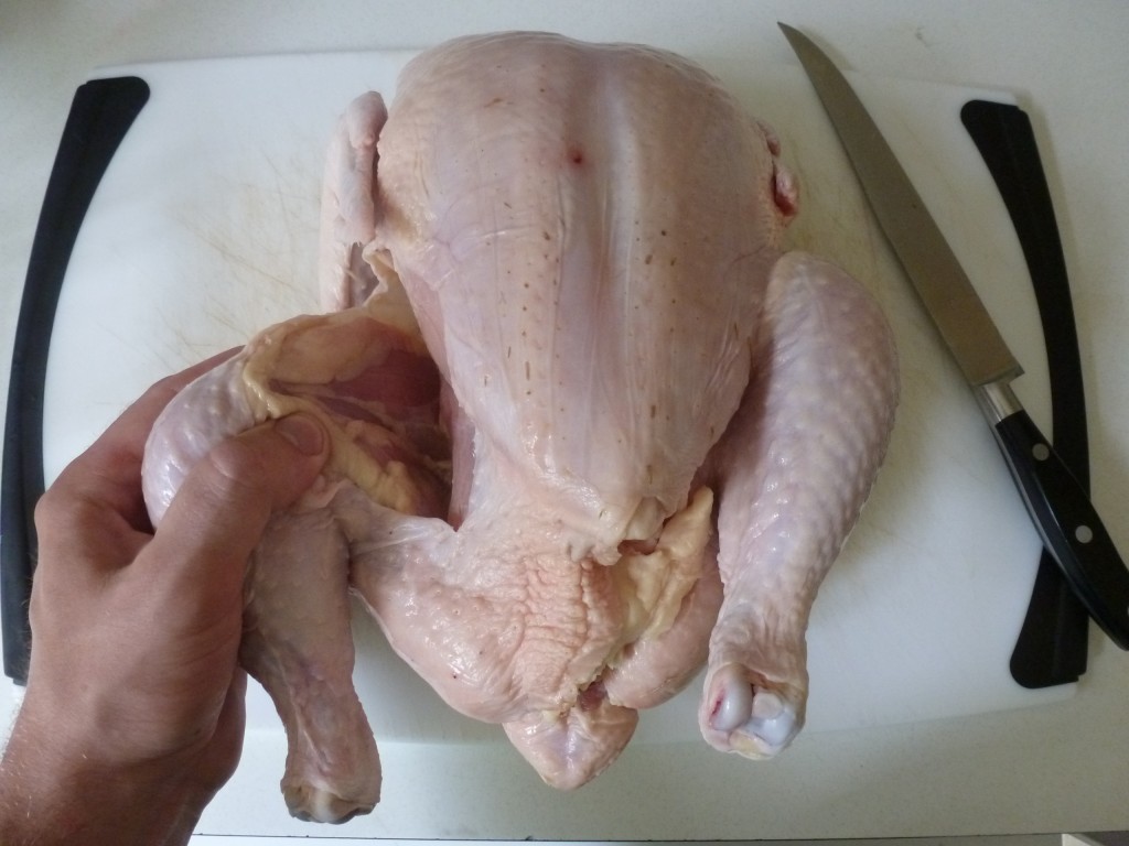 Cutting the skin between the leg and body of the chicken