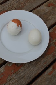 A fresh hard-cooked egg with pock marks, next to an old hard-cooked egg with a perfectly smooth surface.