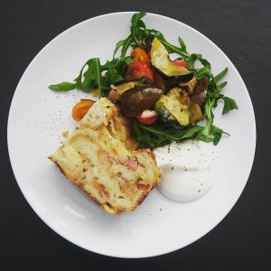 A slice of butcher's cake with a dollop of crème fraîche and a salad.