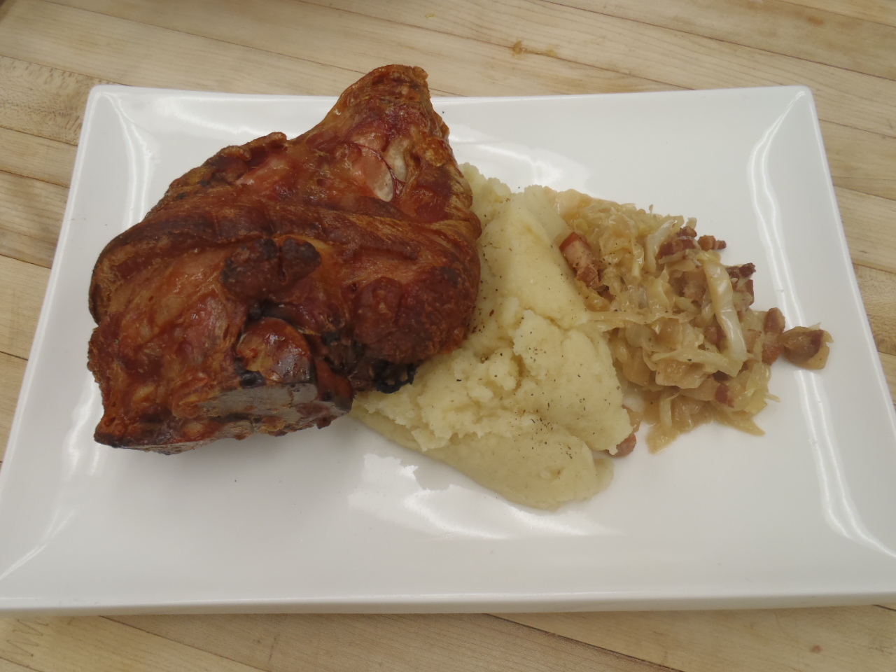 A roast ham hock with mash potatoes and braised cabbage