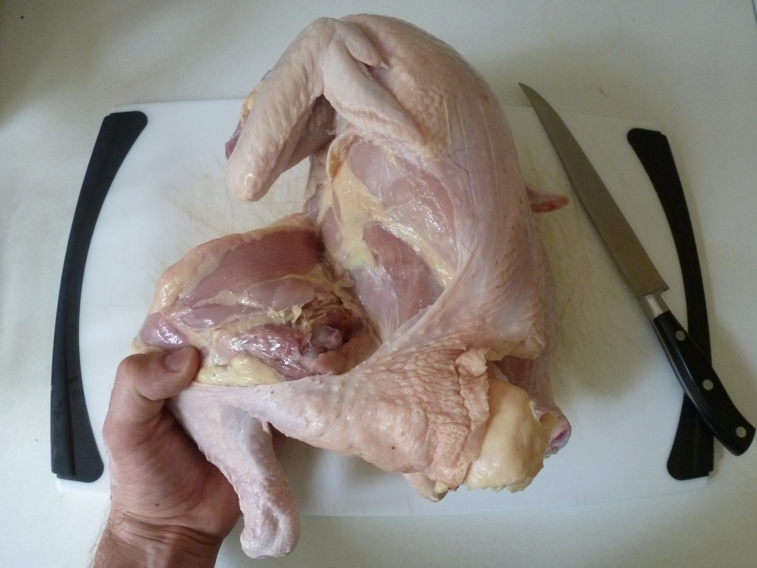 Bending the leg of the chicken back to pop it out of its socket