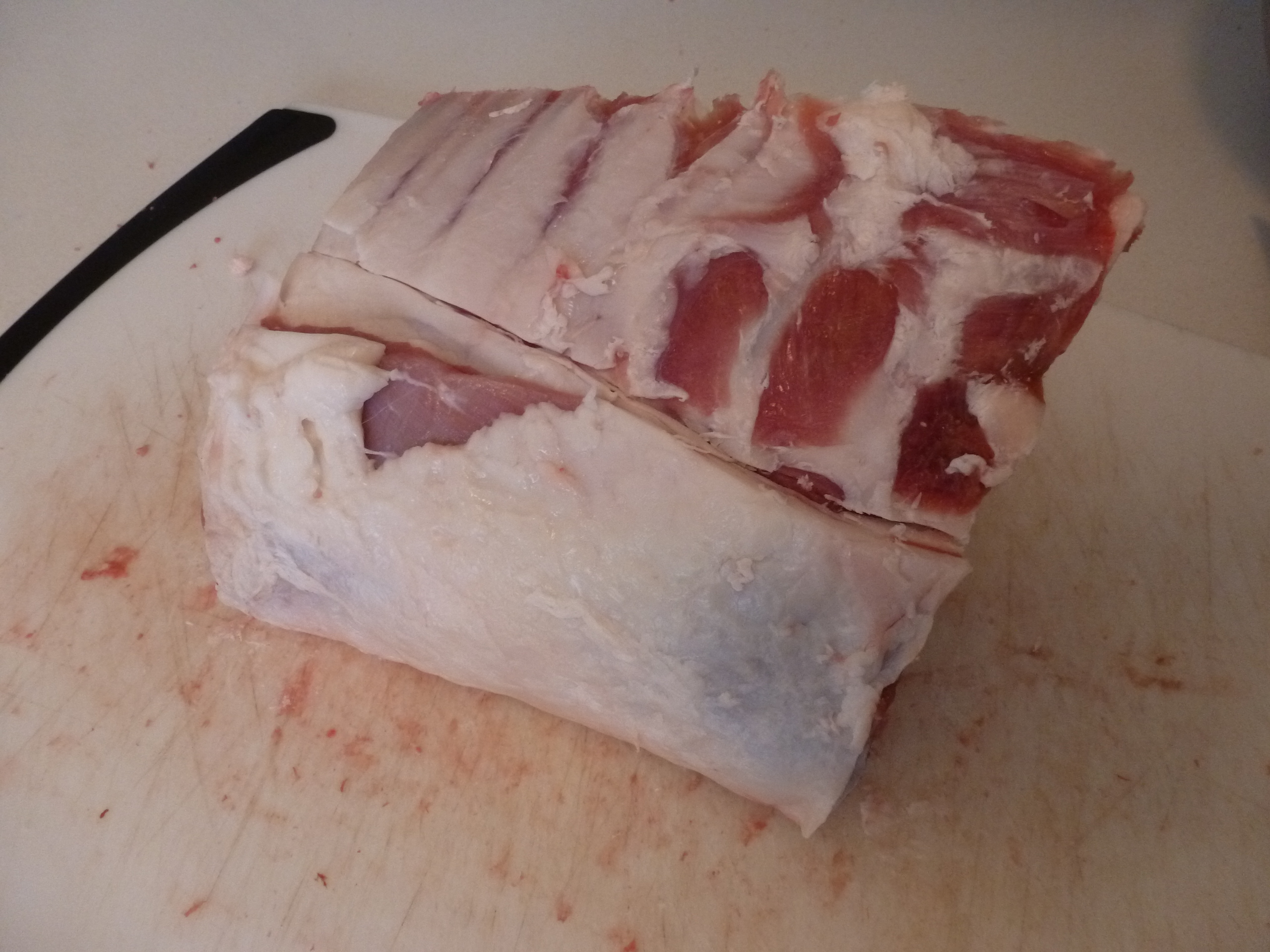 Cutting away the fat cap to expose the ribs on a lamb rack