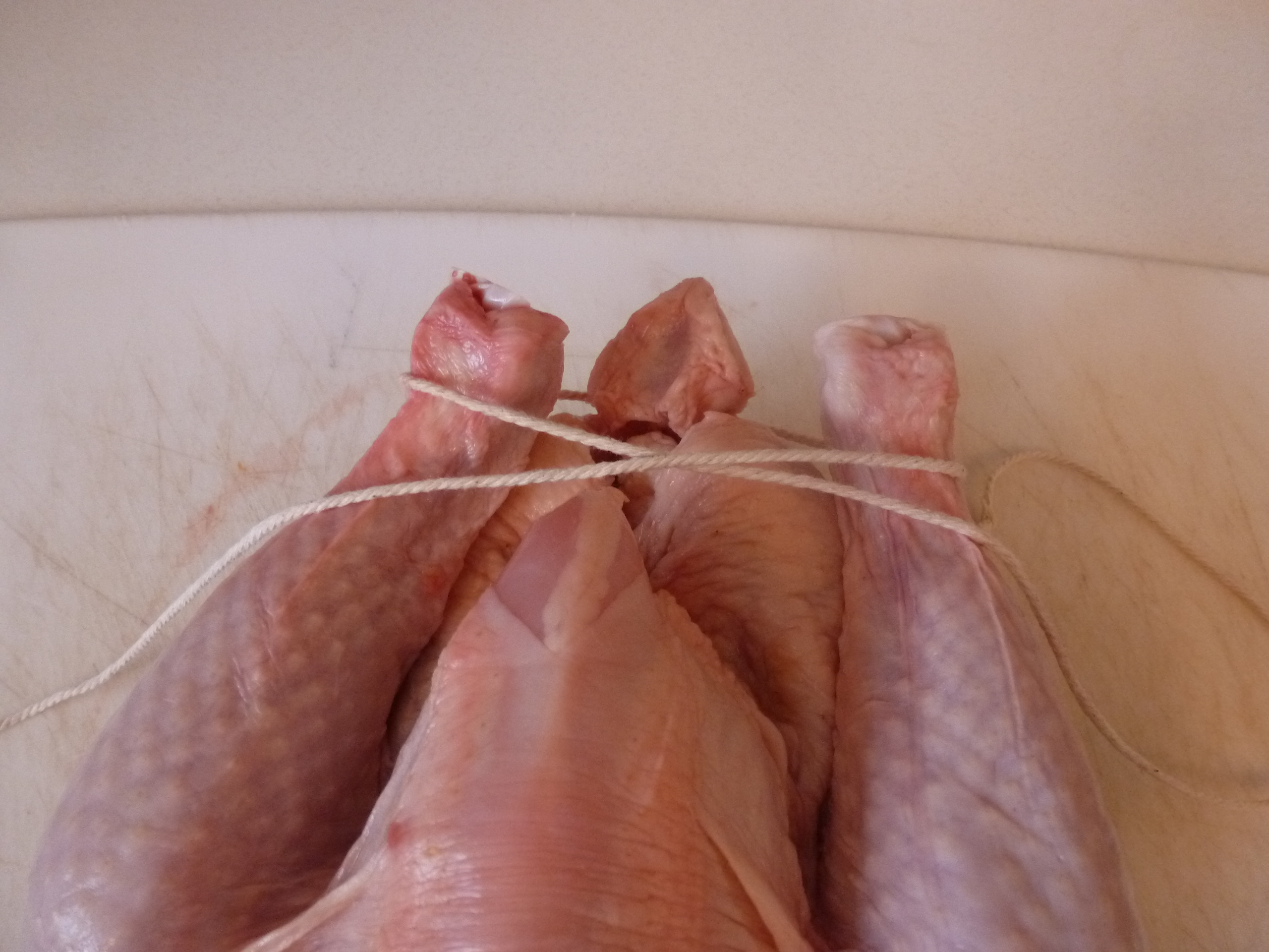 Looping twine around the chicken's tail and legs