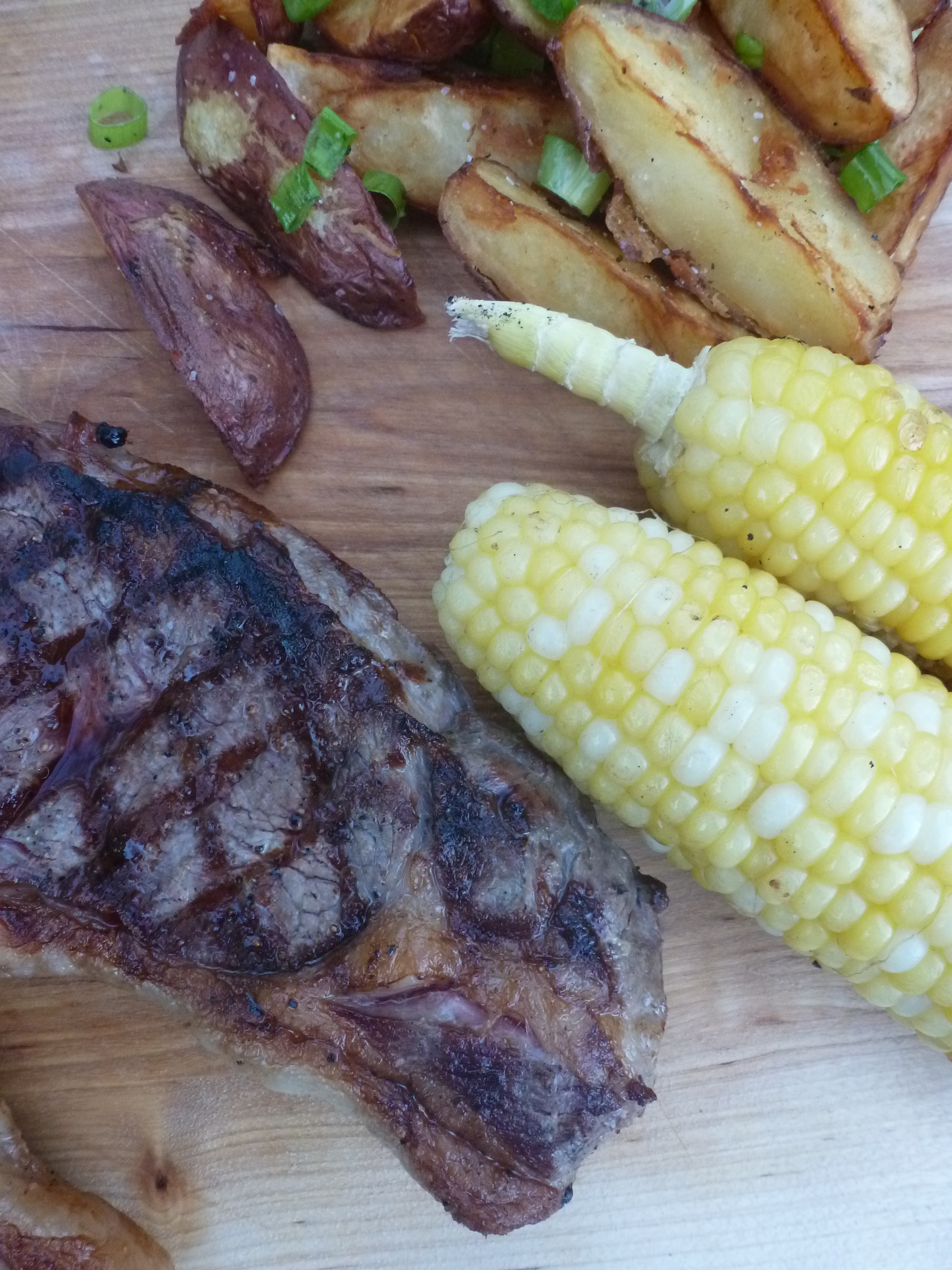 Strip steak, corn on the cob, and steak fries