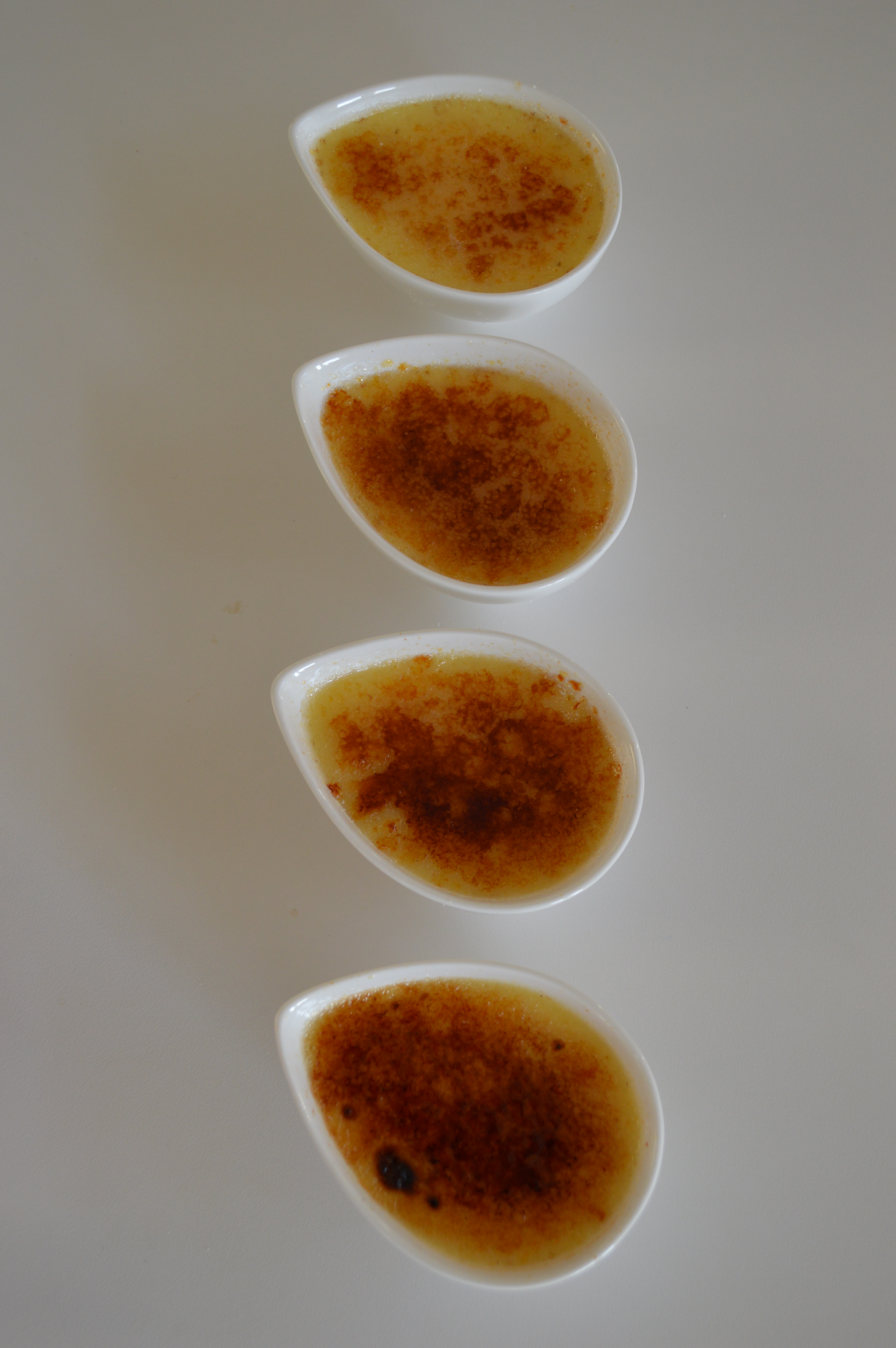 Four ramekins displaying the varying acceptable degrees of burnt sugar on crème brûlée