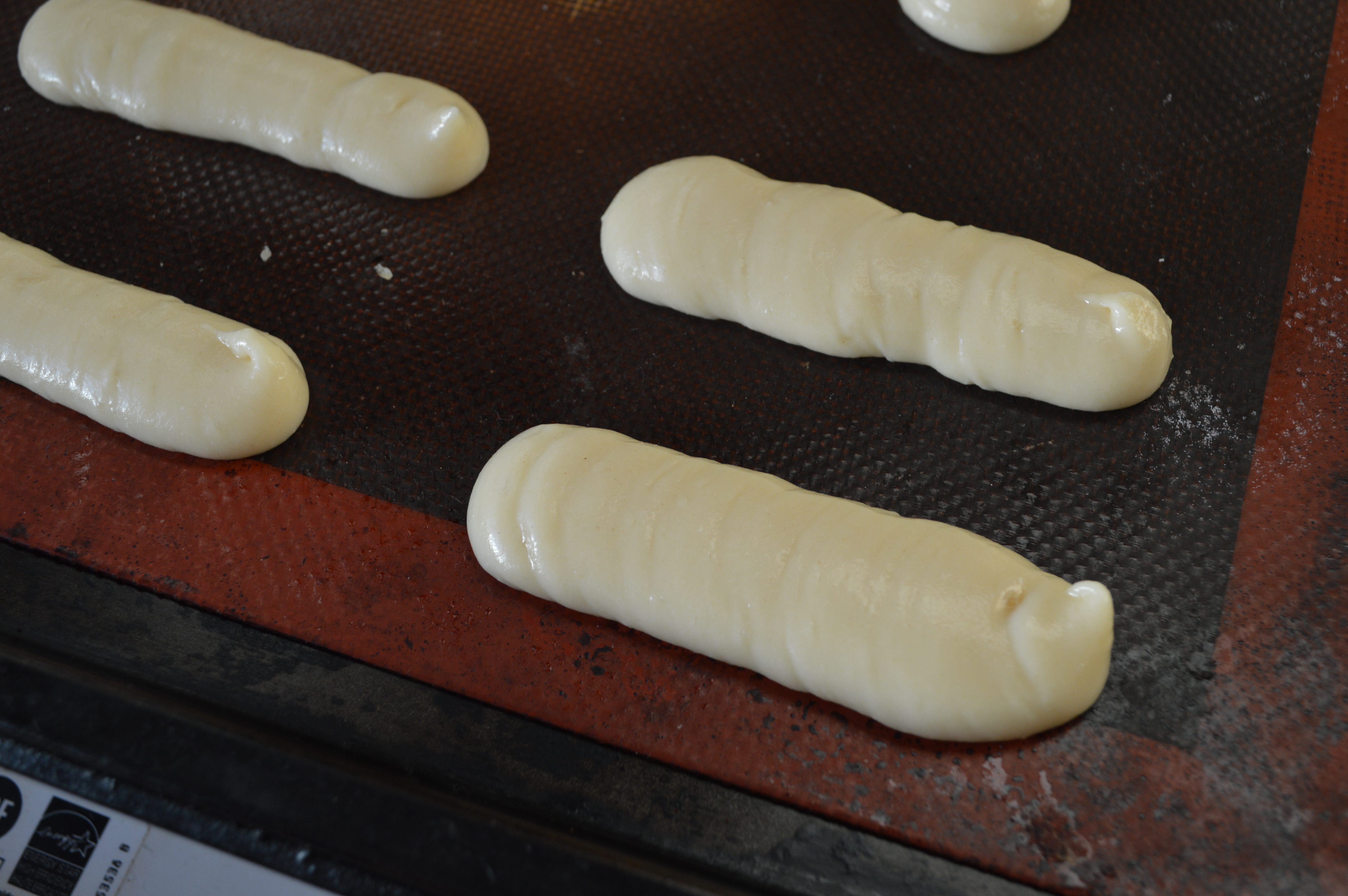 Piping choux pastry to make éclairs