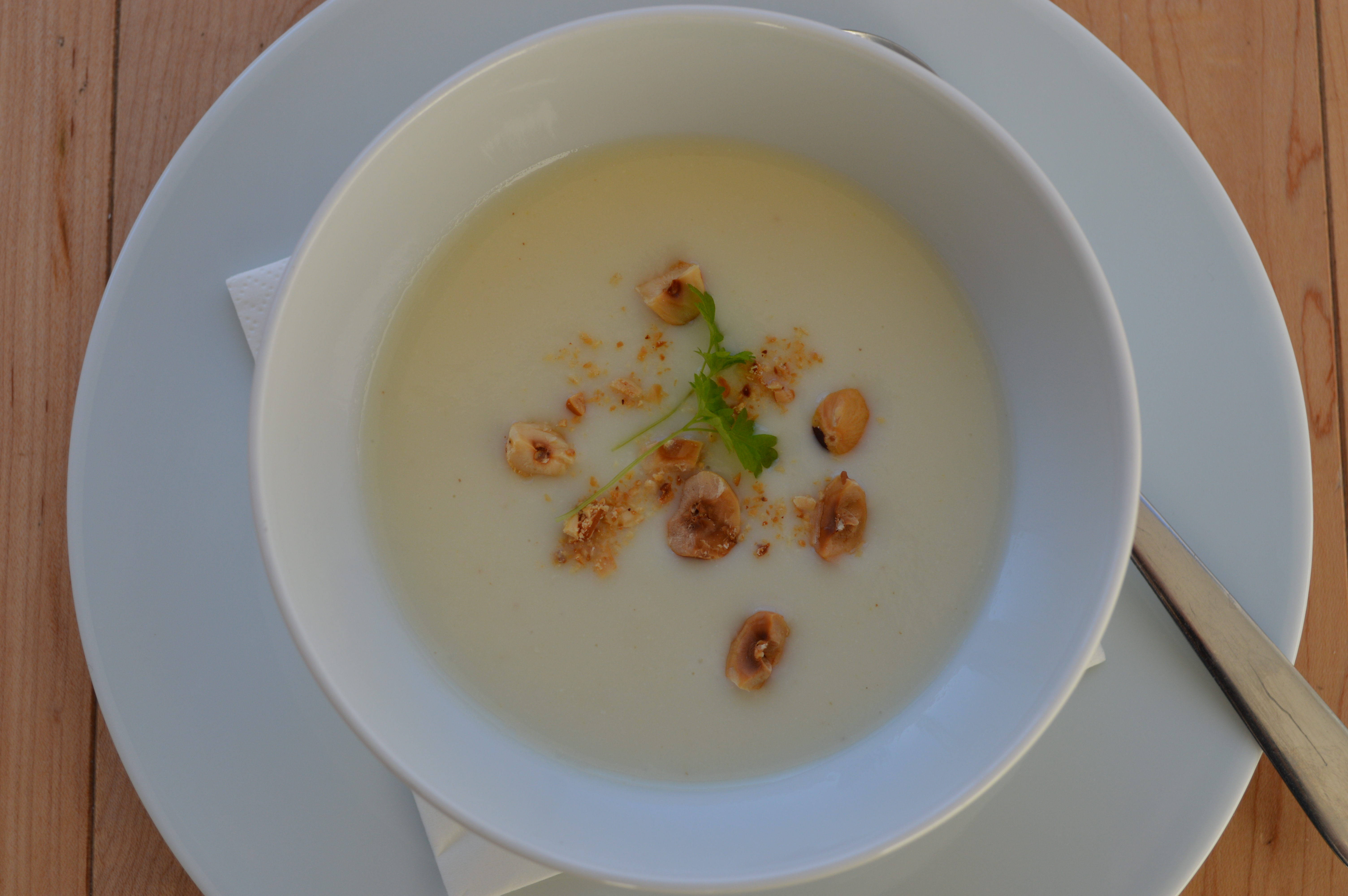 Bowl of parsnip and pear soup, garnished with toasted hazelnuts and chervil