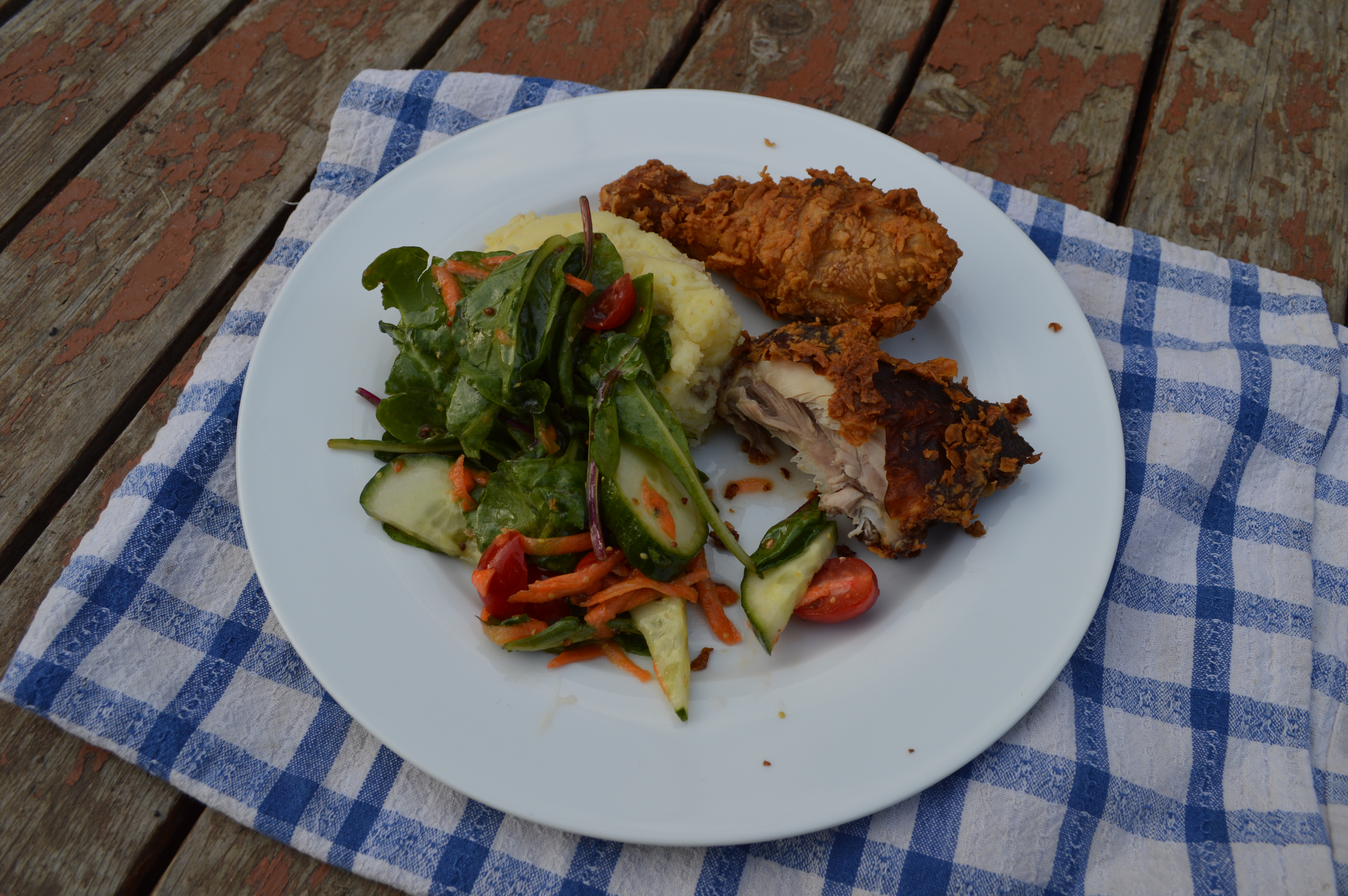 A plate of fried chicken, buttermilk mash potatoes, and green salad