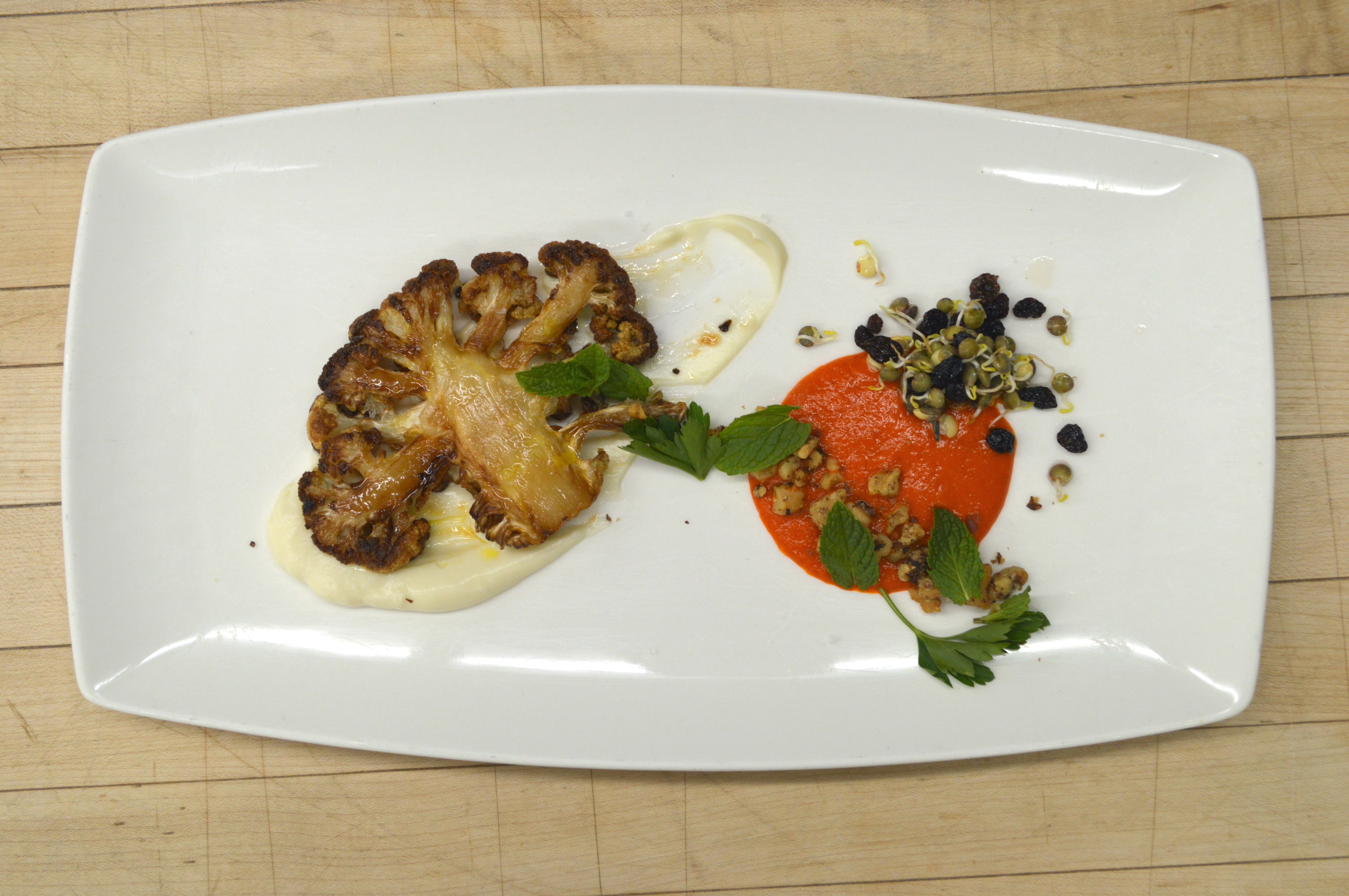 A dish of roasted cauliflower, red peper, walnut, currant, sprouted lentil, and mint.
