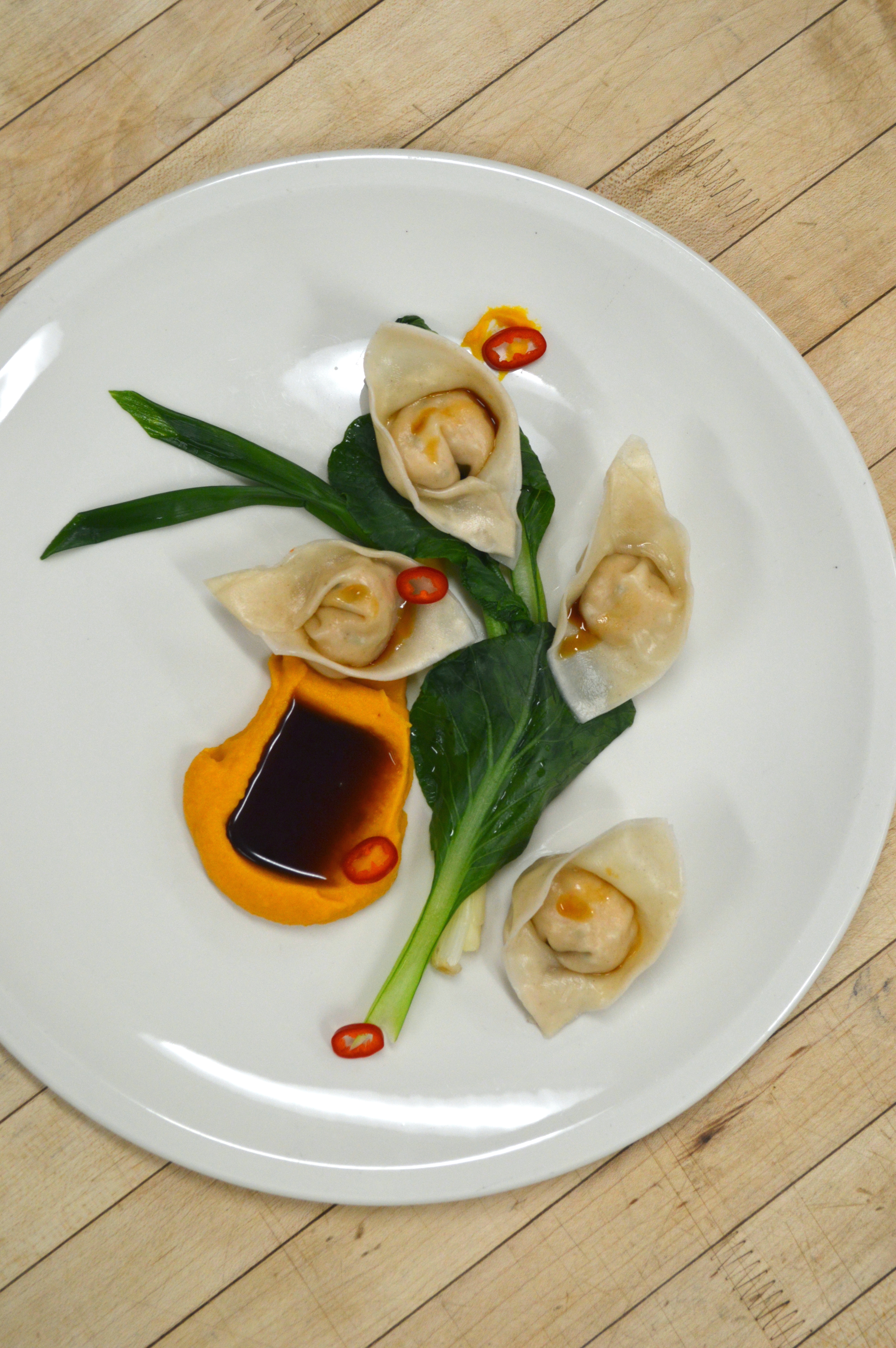 Salmon wontons with gai choi, scallion, soy dipping sauce, and chili.