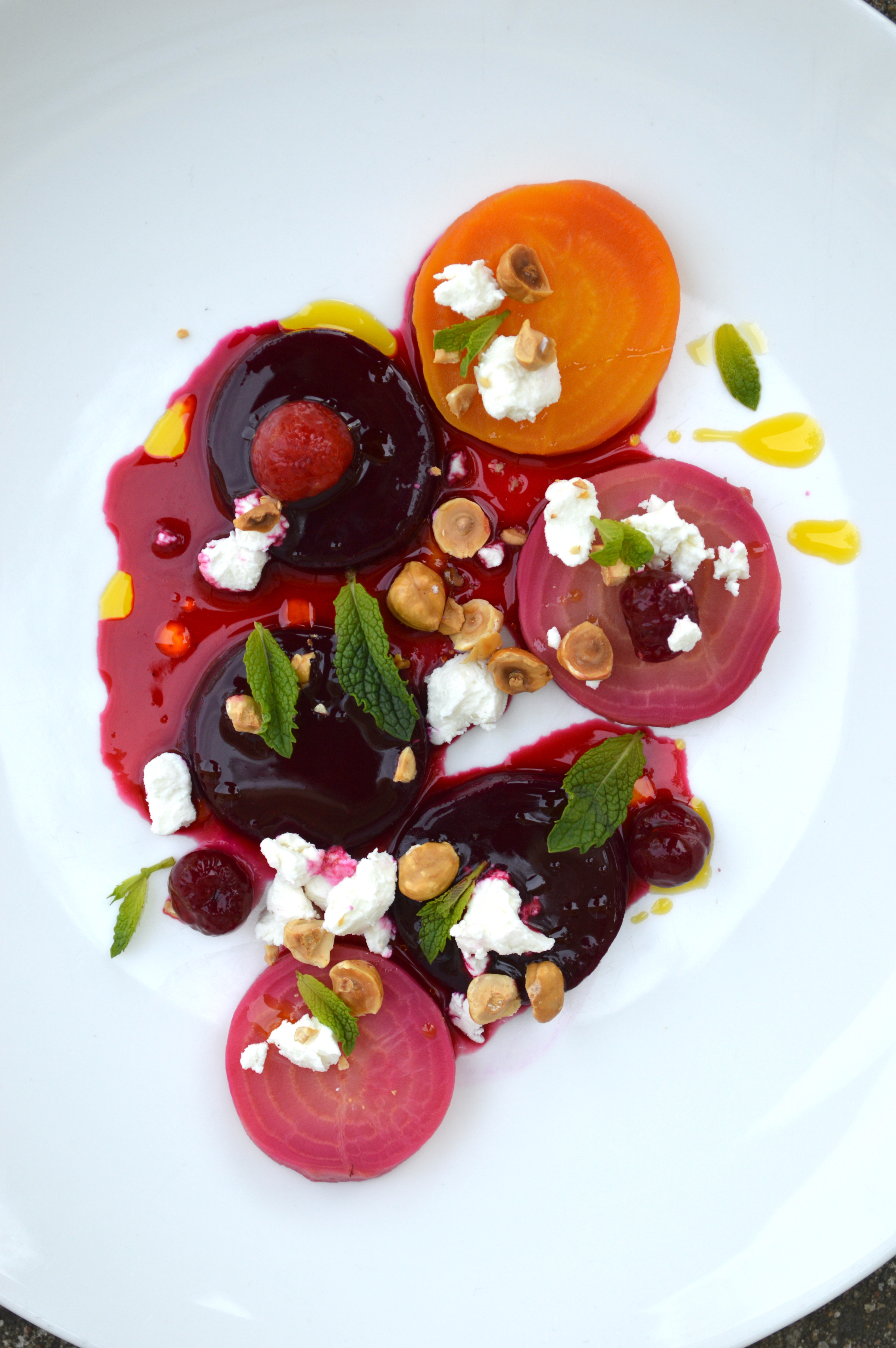 A colourful beet salad with goat cheese, mint, cherries, and hazelnuts.